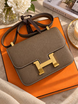 Hermès Constance 24 Brown Epsom Leather Crossbody Shoulder Bag displayed with its orange box.